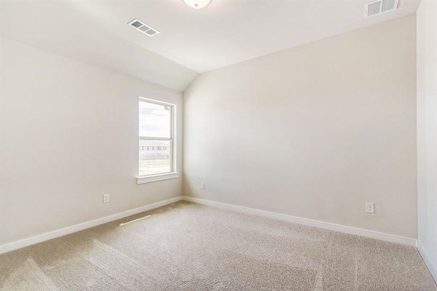 Spare room featuring light colored carpet and lofted ceiling
