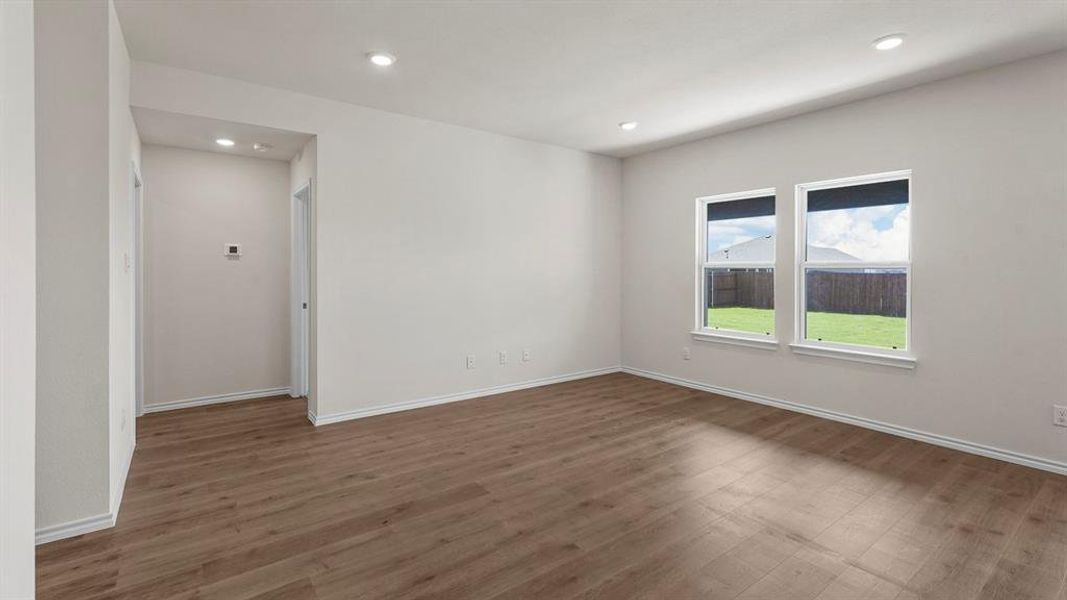 Spacious room featuring wood-finish flooring, recessed lighting, and two windows with roller shades