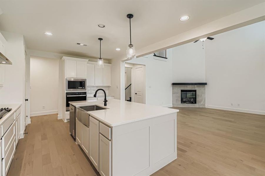 Kitchen featuring white cabinets, a tile fireplace, recessed lighting, open floor plan, and pendant lighting Kitchen featuring white cabinets, a tile fireplace, recessed lighting, open floor plan, and pendant lighting