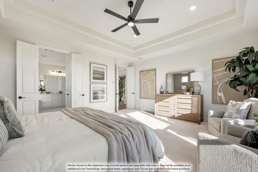 Master bedroom with tray ceiling, ceiling fan, wood dresser, and ensuite bathroom access