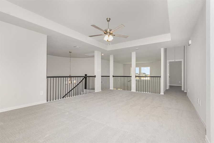 Unfurnished room with light colored carpet, a raised ceiling, and a chandelier