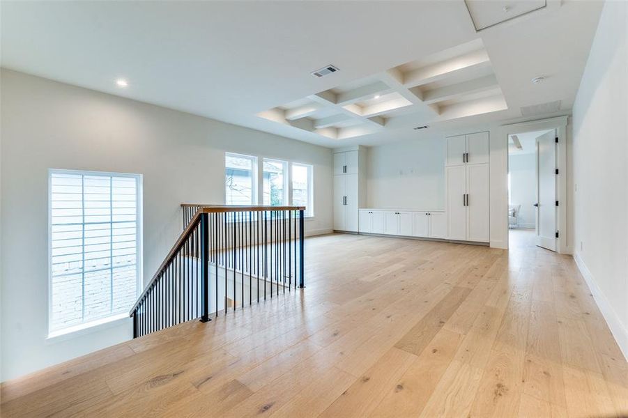 Spare room featuring beam ceiling, coffered ceiling, and light wood-type flooring