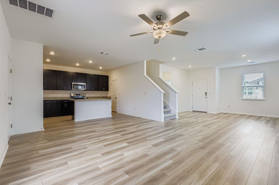 Unfurnished living room featuring stairway, light wood-style flooring, a ceiling fan, and recessed lighting Unfurnished living room featuring stairway, light wood-style flooring, a ceiling fan, and recessed lighting