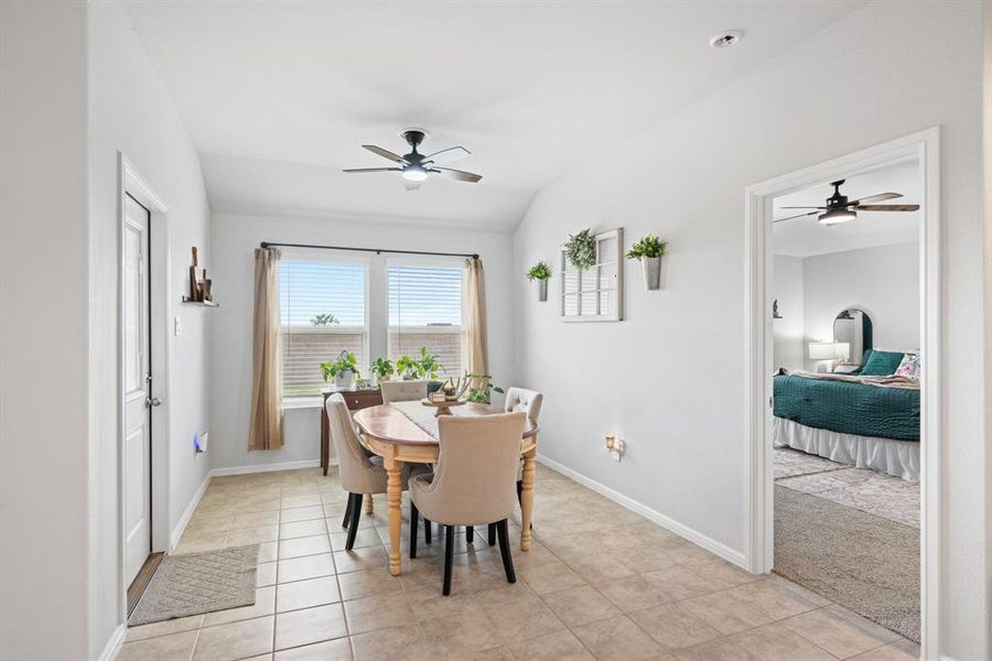 Dining space featuring ceiling fan, light tile patterned floors, and lofted ceiling
