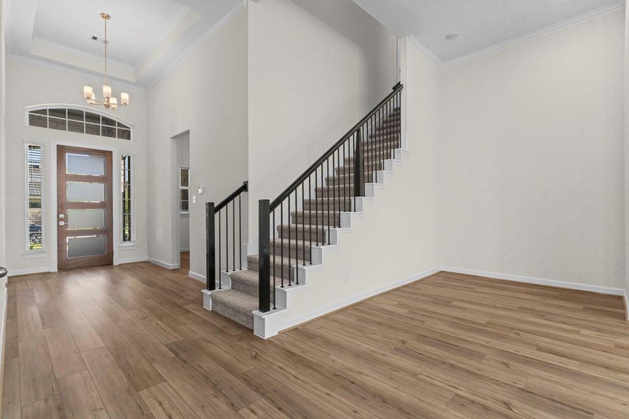 Impressive entryway with soaring ceilings, wood-look large plank tile flooring, and views of the sweeping iron staircase. Impressive entryway with soaring ceilings, wood-look large plank tile flooring, and views of the sweeping iron staircase.