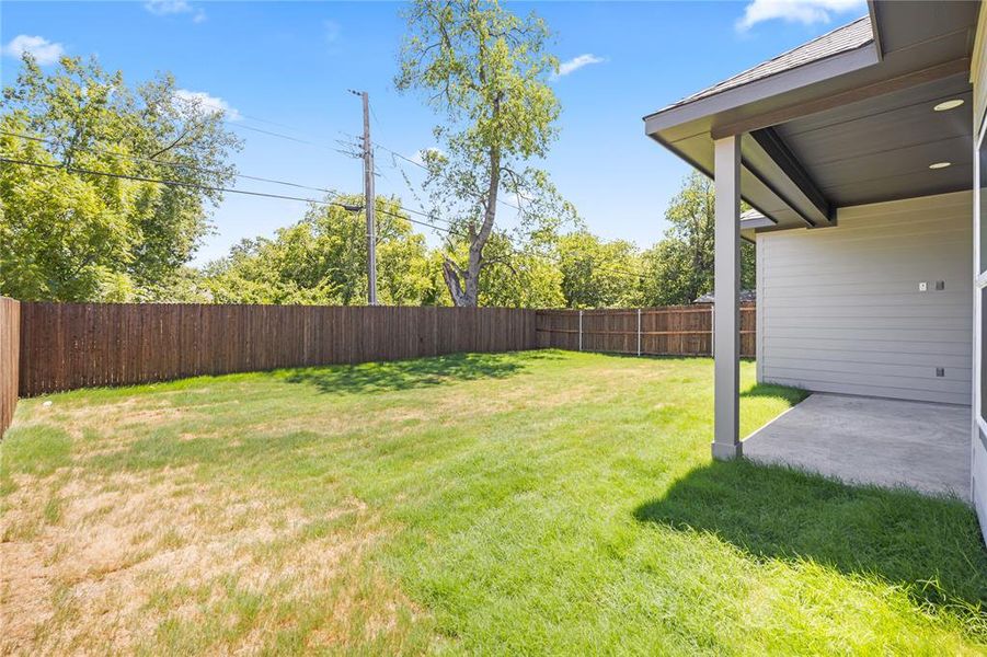 Expansive backyard featuring a privacy fence, a concrete patio, and a covered patio area with recessed lighting