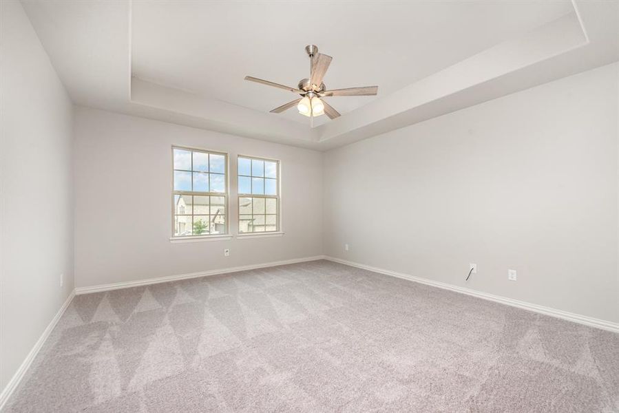 Unfurnished room featuring light colored carpet, a raised ceiling, and ceiling fan