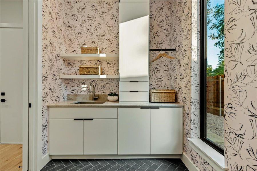Oversized laundry room with custom cabinetry and designer, high durability wallpaper.  Recessed washer/dryer location creates extra space.