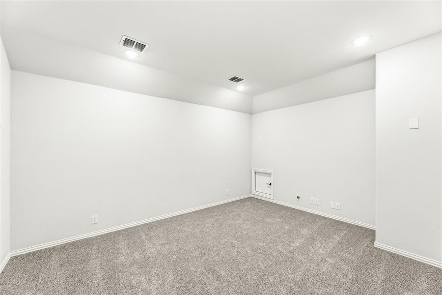Empty room with gray carpet, white walls, recessed lighting, and a small access panel on the wall