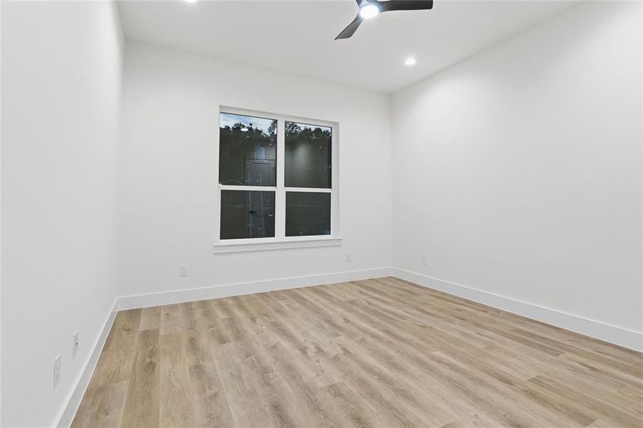 Empty room with ceiling fan, light wood finished floors, and recessed lighting
