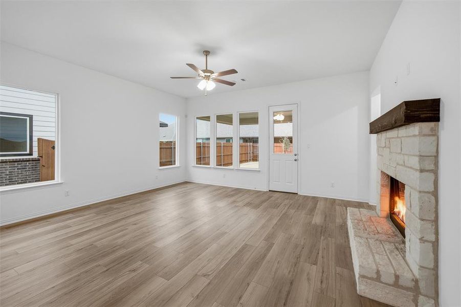Unfurnished living room with light wood-style floors, a fireplace, and ceiling fan