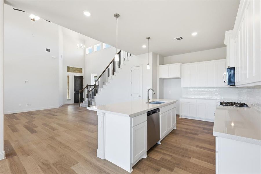 Kitchen featuring a kitchen island with sink, white cabinetry, open floor plan, and a high ceiling