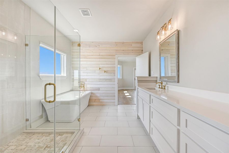 The primary bath feels like a private spa retreat with a freestanding soaking tub, oversized glass shower, and expansive double vanity. Soft natural light and calming finishes create a serene space to recharge after a day on the coast.