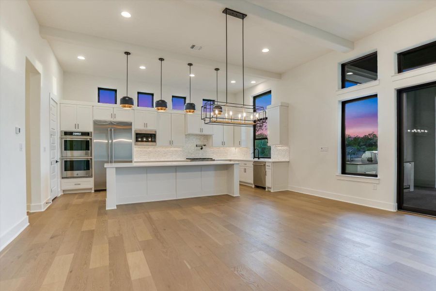 Kitchen featuring white cabinets, a center island, backsplash, and built in appliances