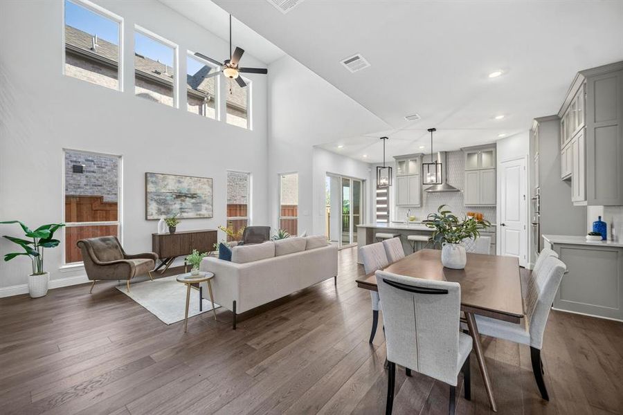 Open-concept interior featuring wood-finish flooring, high ceilings with upper windows, and a ceiling fan