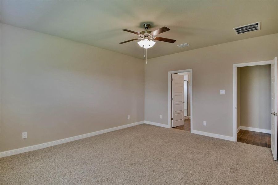 Unfurnished bedroom featuring dark carpet and a ceiling fan Unfurnished bedroom featuring dark carpet and a ceiling fan