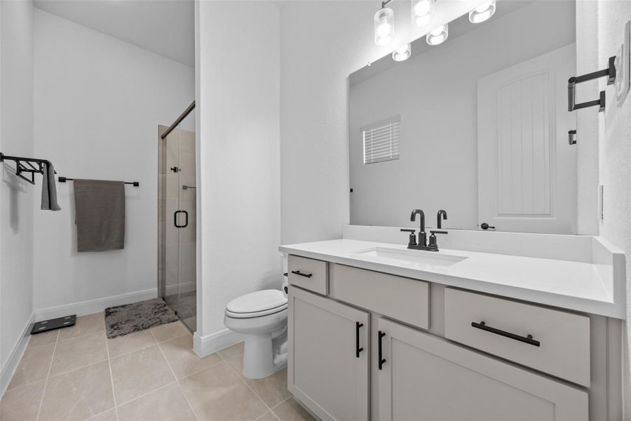 A well-lit bathroom with a modern vanity, shower, and pristine tiled flooring offers refreshing convenience. A well-lit bathroom with a modern vanity, shower, and pristine tiled flooring offers refreshing convenience.