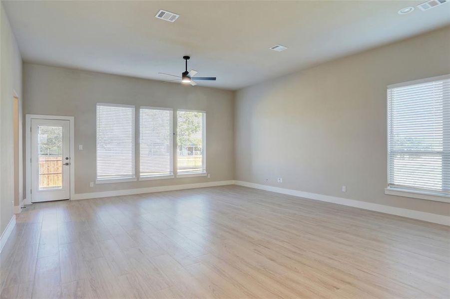 Empty room featuring plenty of natural light, light wood finished floors, and a ceiling fan Empty room featuring plenty of natural light, light wood finished floors, and a ceiling fan
