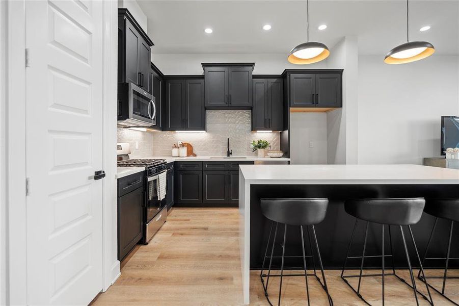 Sleek modern kitchen featuring elegant black cabinetry, stainless steel appliances, and a spacious island with stylish pendant lighting, perfect for entertaining. Sleek modern kitchen featuring elegant black cabinetry, stainless steel appliances, and a spacious island with stylish pendant lighting, perfect for entertaining.