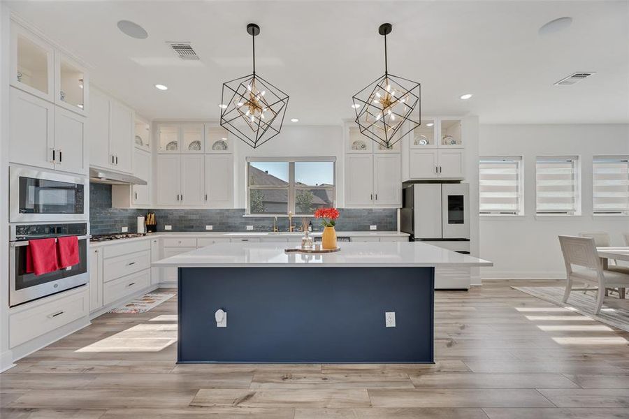 Kitchen featuring white cabinetry, decorative light fixtures, backsplash, stainless steel appliances, and recessed lighting
