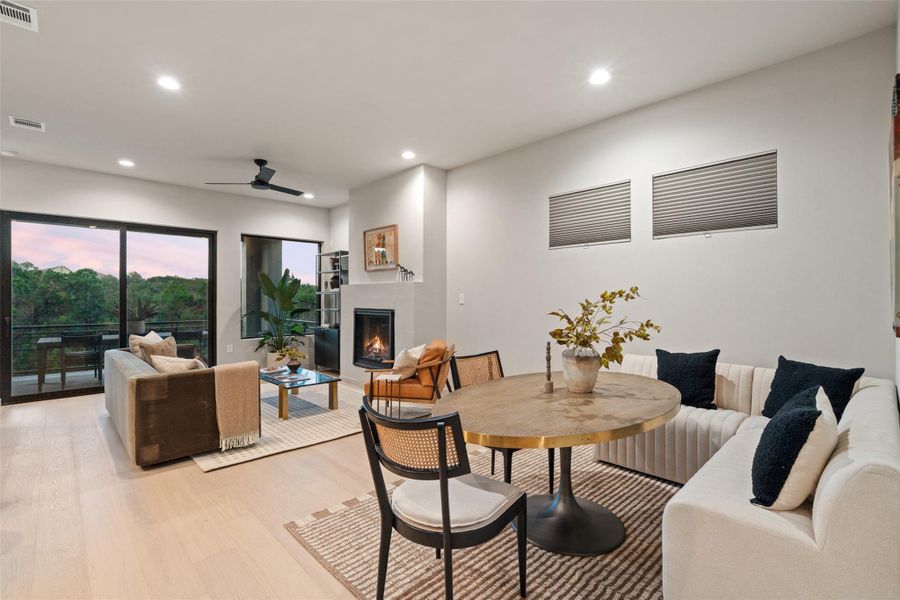 A refined open-concept living and dining area features a cozy fireplace, abundant natural light, and access to an outdoor balcony. A refined open-concept living and dining area features a cozy fireplace, abundant natural light, and access to an outdoor balcony.