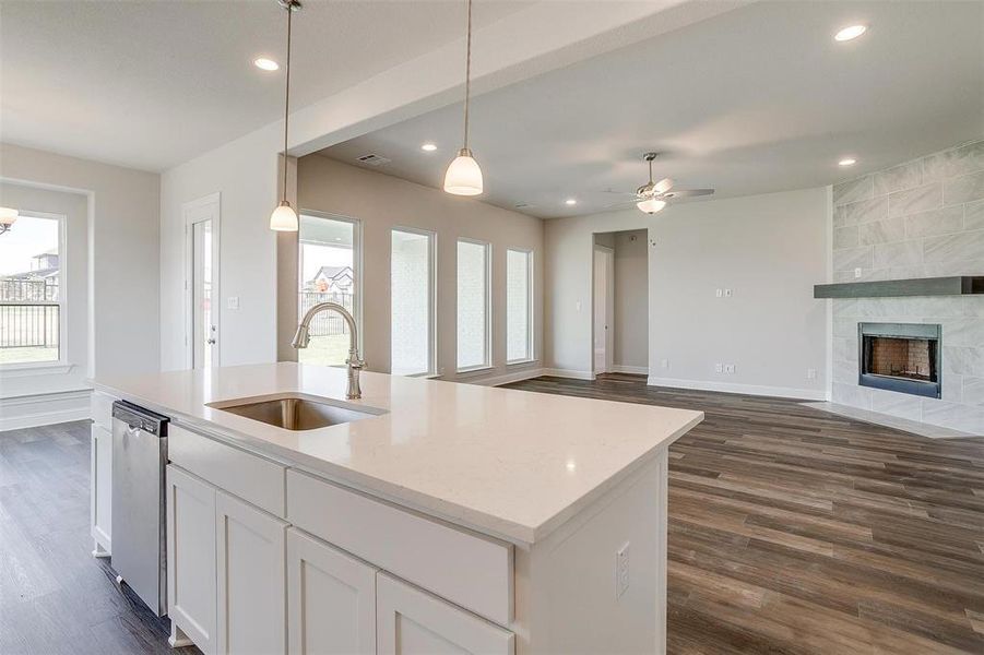 Kitchen with sink, dark wood-type flooring, a tile fireplace, and a center island with sink