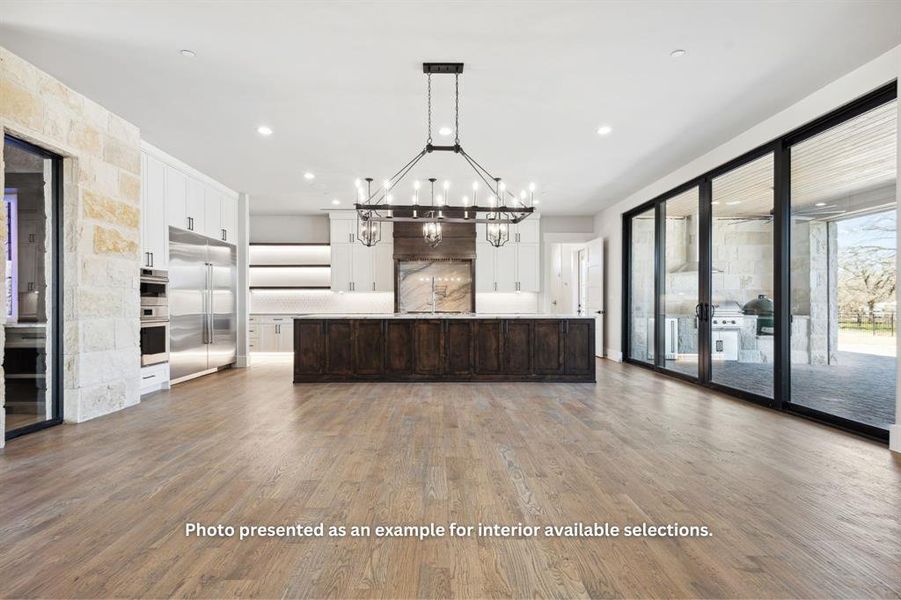 Kitchen with an island with sink, built in refrigerator, and hardwood / wood-style floors