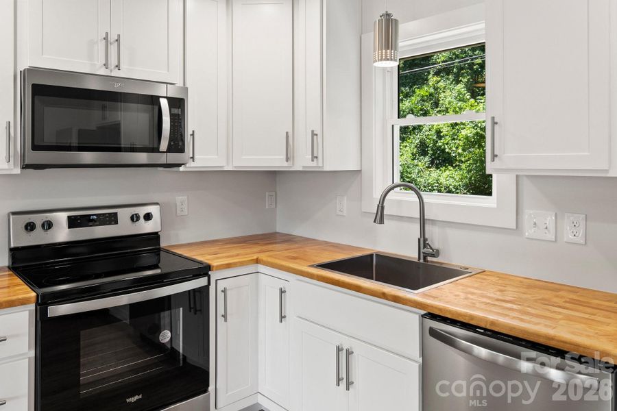 Fresh white cabinets, butcherblock counters, and stainless appliances