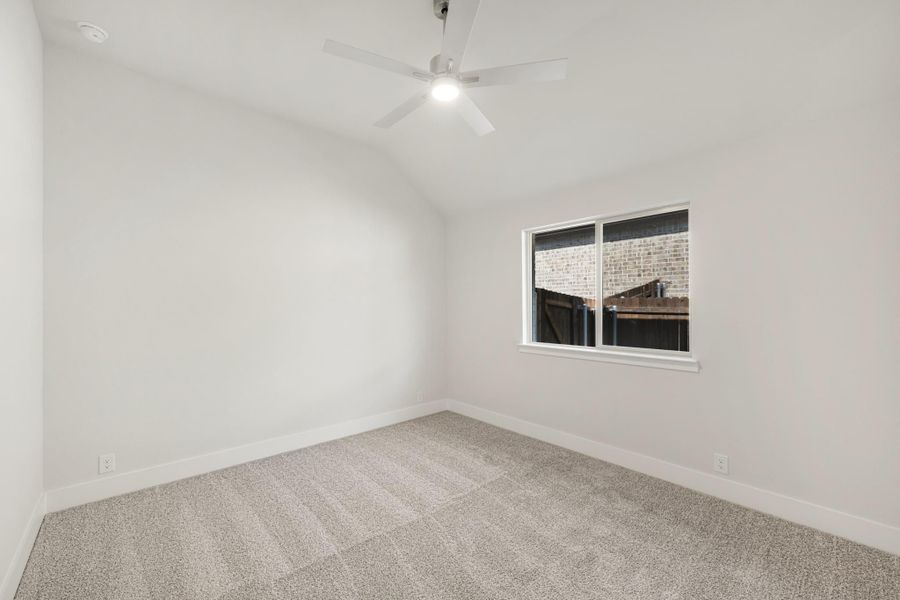 Empty bedroom with vaulted ceiling, ceiling fan, carpet flooring, and single window Empty bedroom with vaulted ceiling, ceiling fan, carpet flooring, and single window