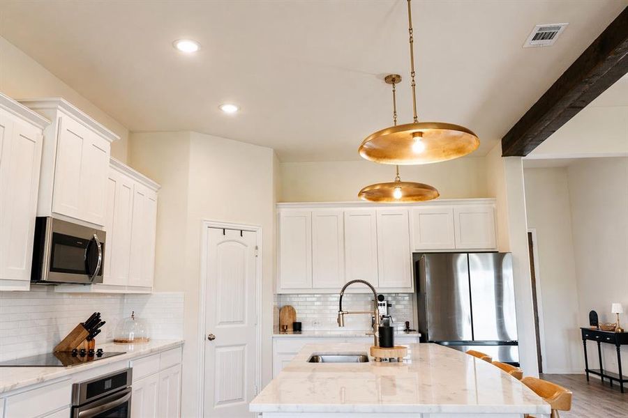 Modern kitchen featuring white shaker cabinetry, stainless steel appliances, a subway tile backsplash, recessed lighting, and a kitchen island with pendant lighting