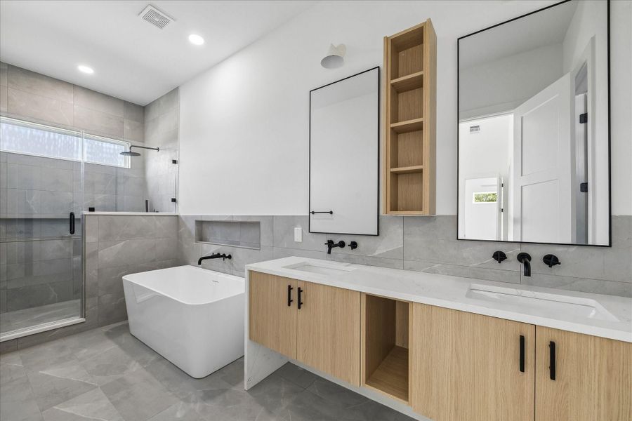 Dual floating style vanities, quartz countertops, oversized mirrors, and full height tile create a spa inspired primary bath designed for everyday luxury.