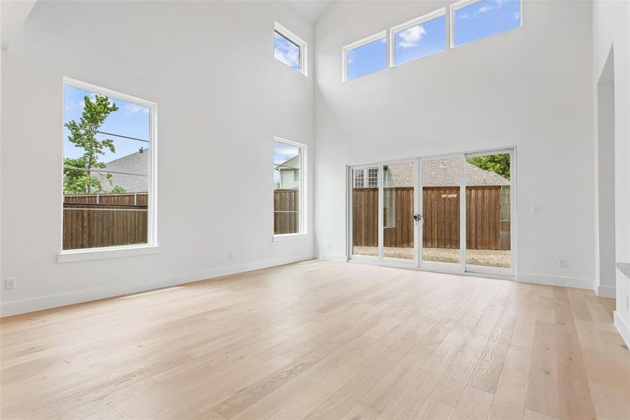 Unfurnished living room featuring light wood-type flooring and a high ceiling