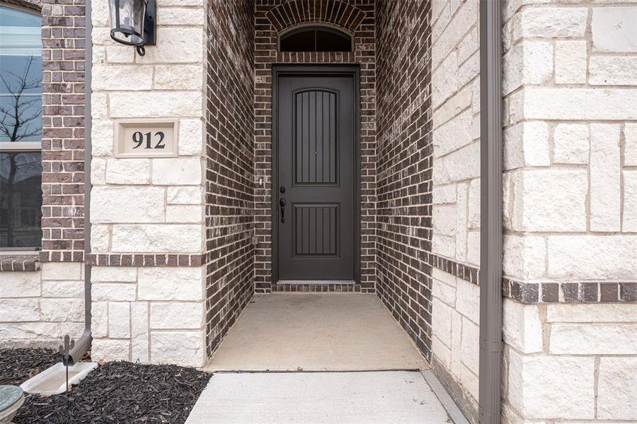 Covered front porch with decorative lighting and wood front door