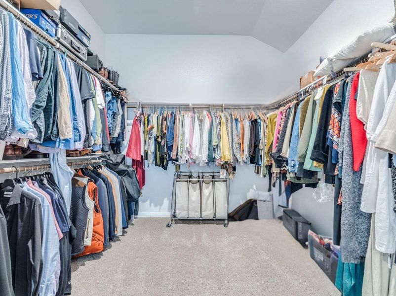Primary walk in closet features ample hanging space to create an organized and functional walk-in closet.
