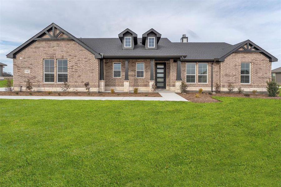View of front of home featuring brick siding, a front yard, and roof with shingles