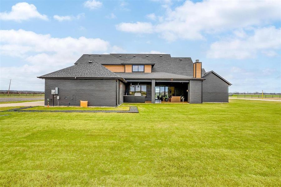 Rear view of property featuring brick siding, a yard, a chimney, and a patio