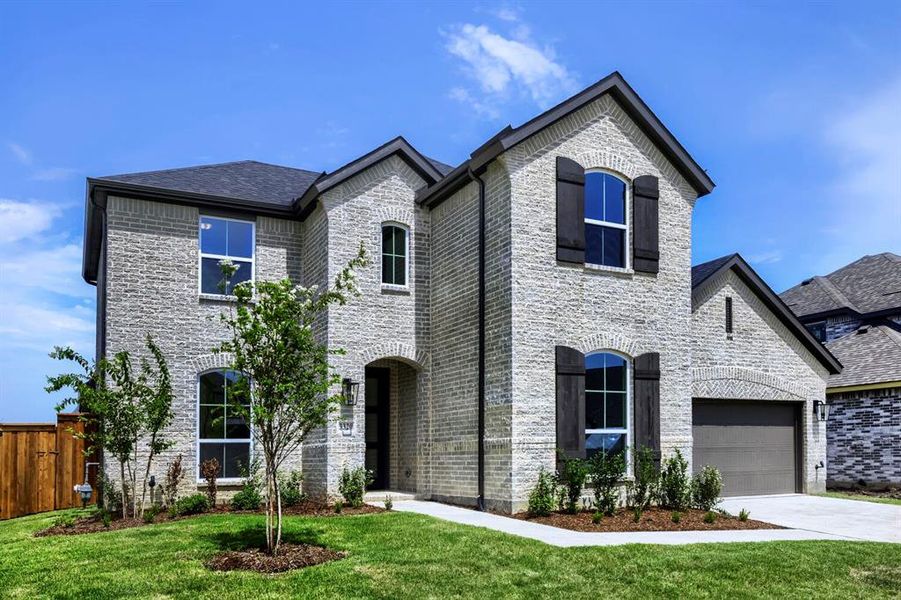 Two-story residence featuring light-colored brick facade and a dark shingle roof Two-story residence featuring light-colored brick facade and a dark shingle roof