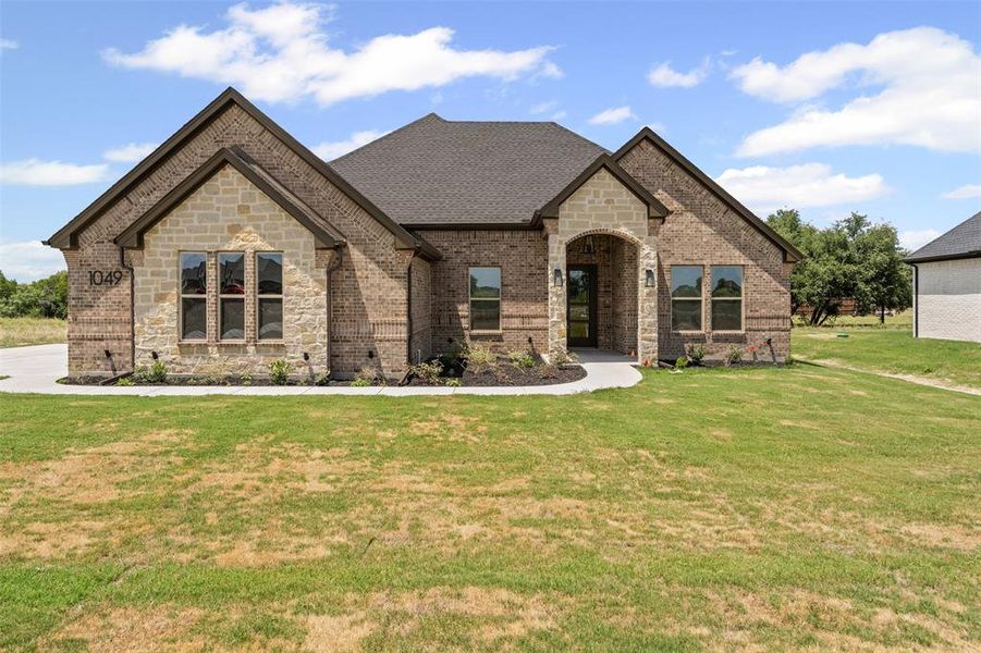 French country home with brick siding, a front lawn, stone siding, and a shingled roof French country home with brick siding, a front lawn, stone siding, and a shingled roof