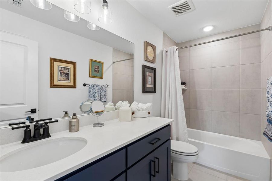 The secondary bath features contemporary finishes, quartz countertops, and a tub-shower combination designed for both style and functionality.