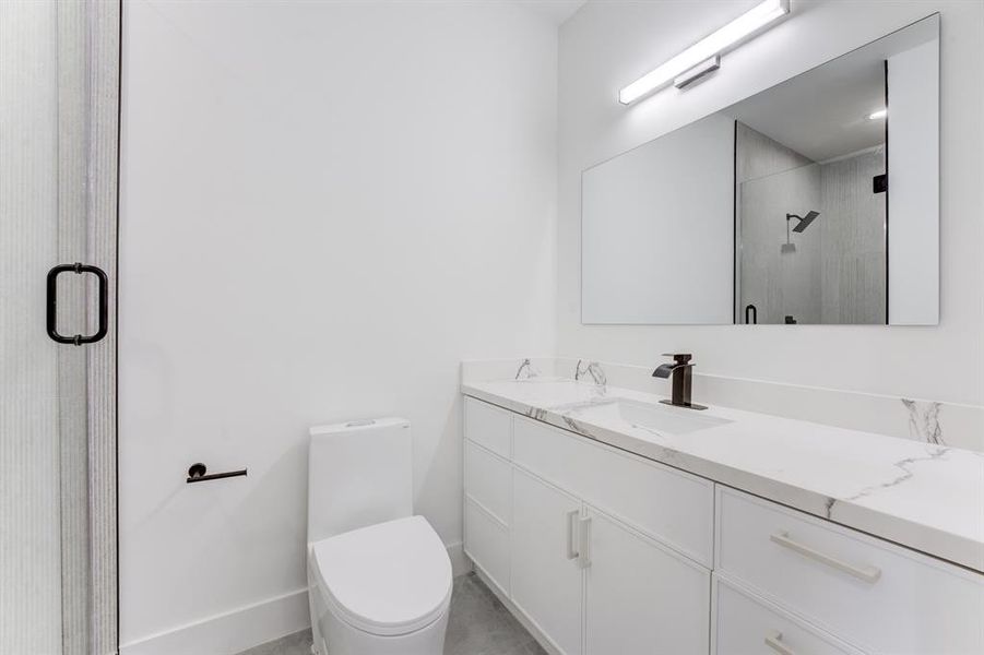 Large frameless mirror, quartz countertop, chic white cabinetry, modern toilet.