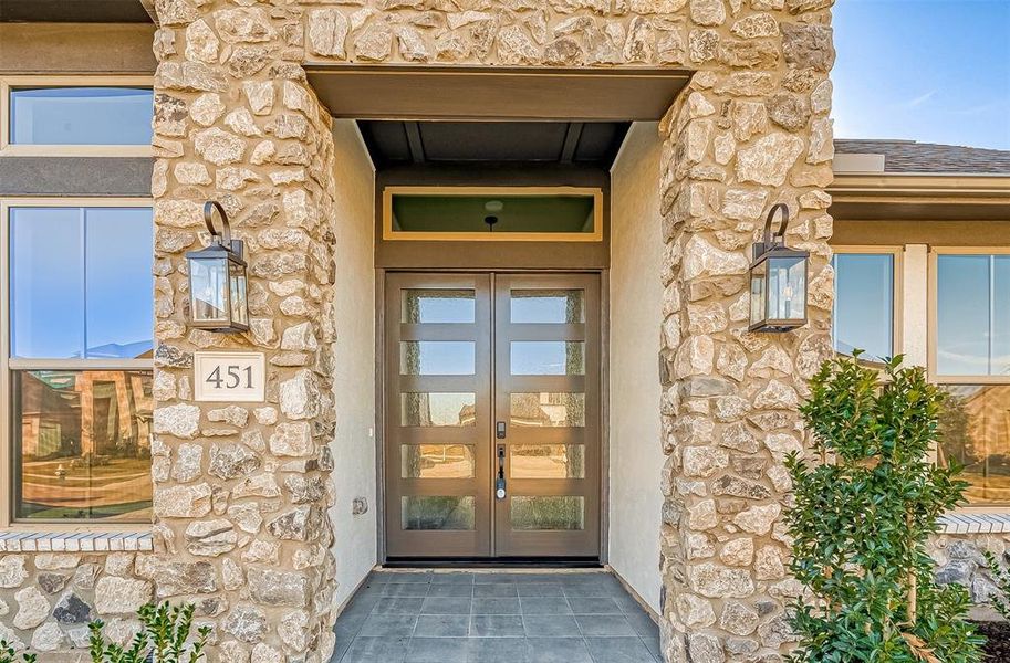 Situated on a spacious corner lot, the home showcases an impressive stucco and stone elevation with an upgraded 8-foot waterfall glass and wood double-door entryway.