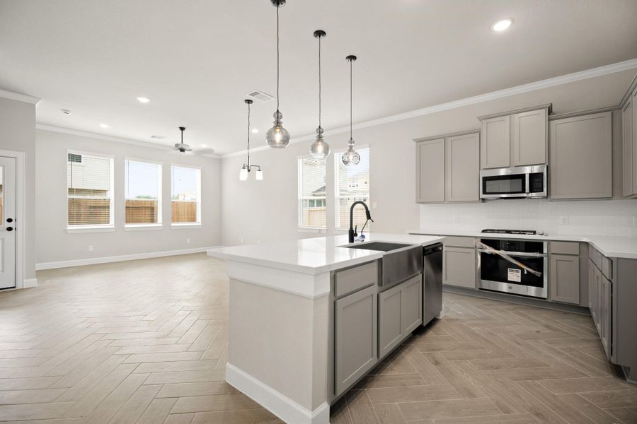Island kitchen with quartz countertops and stainless appliances (*Photo not of actual home and used for illustration purposes only.)