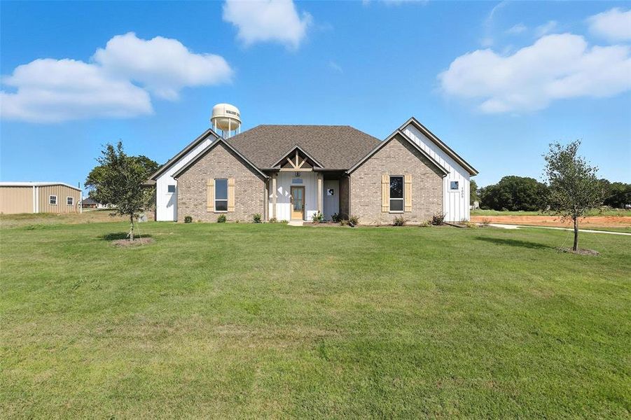 View of front of home featuring a front lawn, brick siding, and board and batten siding View of front of home featuring a front lawn, brick siding, and board and batten siding