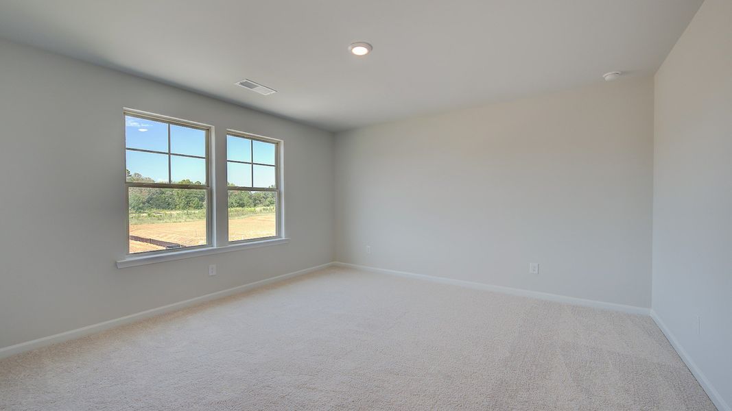 Spacious secondary bedroom with carpet flooring and natural light in the Clarity at Brighton in Locust Grove, GA.