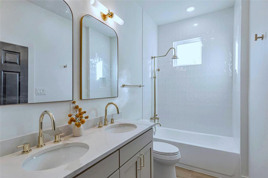 Bathroom with toilet, shower / tub combination, double vanity, and a sink