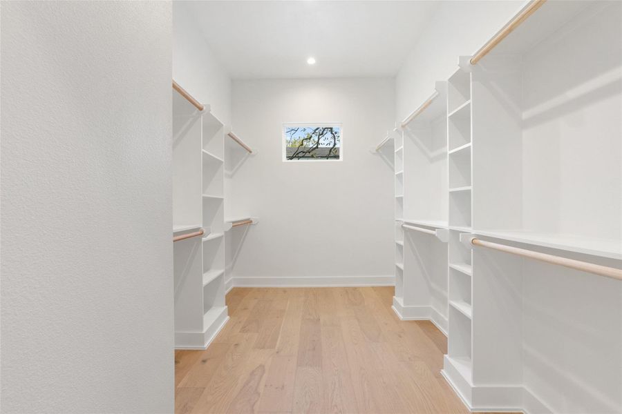 Spacious closet with light wood-style flooring Spacious closet with light wood-style flooring