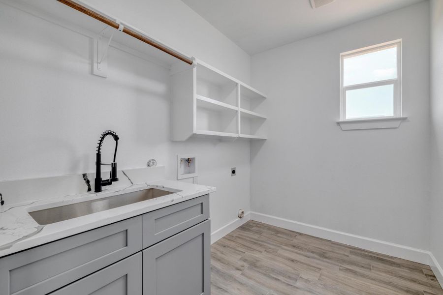 Washroom with hookup for an electric dryer, cabinet space, washer hookup, baseboards, and light wood-type flooring