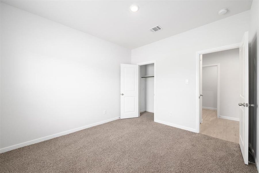 Unfurnished bedroom with light carpet and a closet