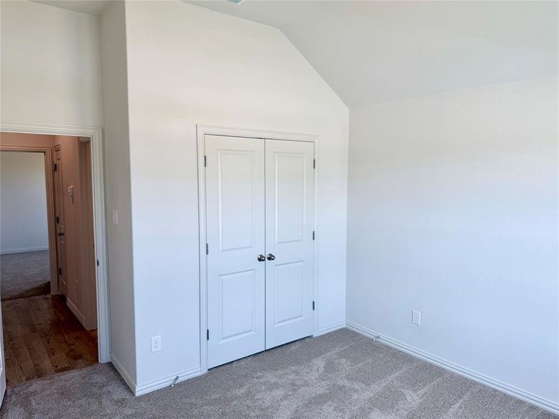 Room featuring plush carpeting, a bi-fold closet with white paneled doors, and white baseboards