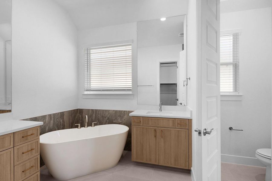 A well-lit primary bathroom presents a freestanding tub alongside dual vanities and modern fixtures.